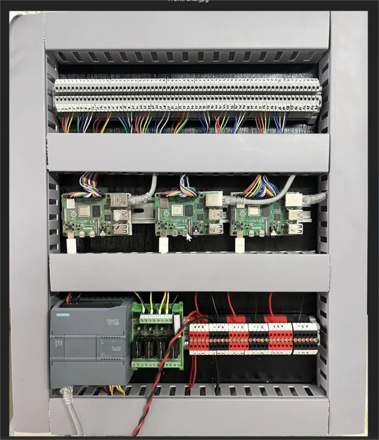 Bay level, up close — single-board-computer IEDs above an industrial PLC and its field wiring.